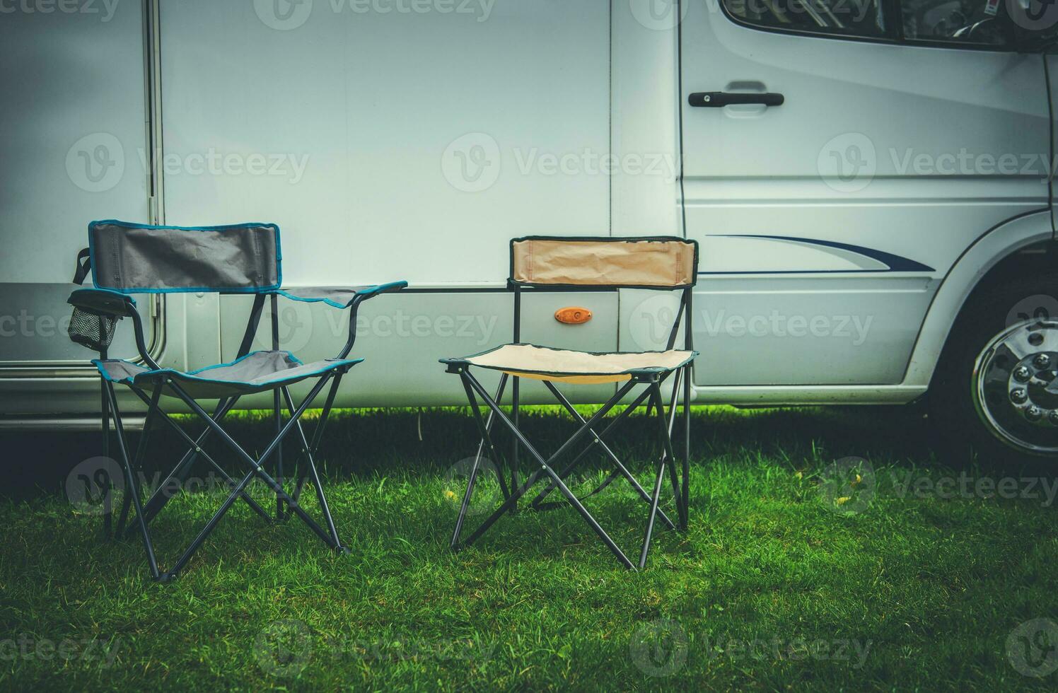 Two Empty Camping Deckchairs in Front of RV Camper photo