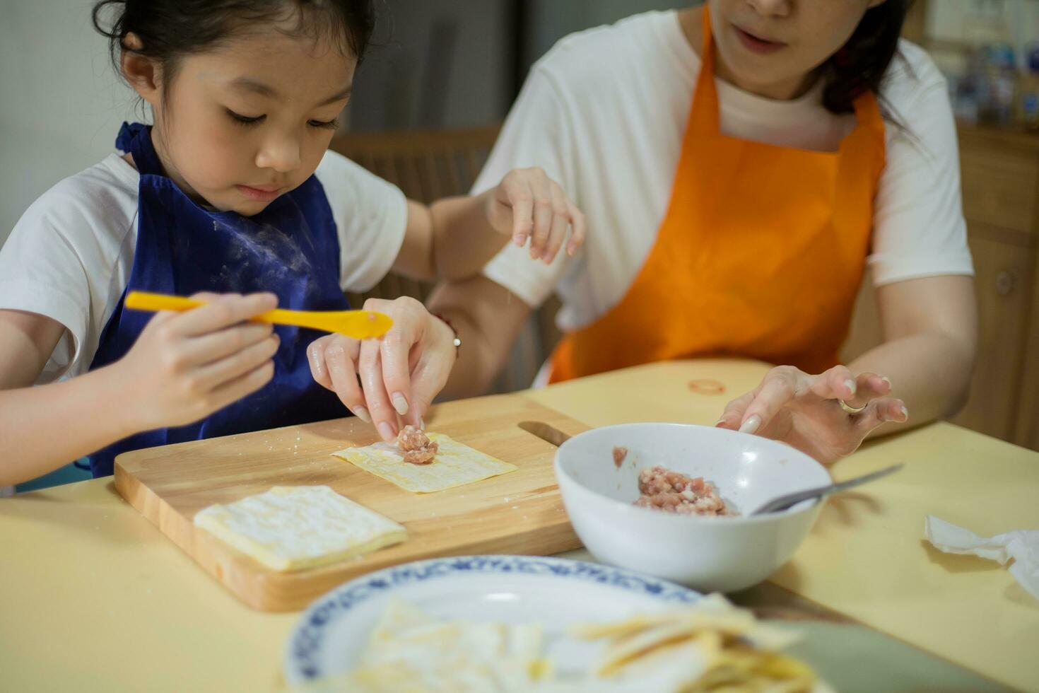 asiático madre y hija son Cocinando comida y teniendo divertido en el cocina. foto