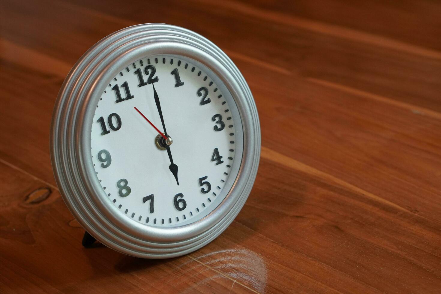 beautiful alarm clock, silver and white, placed on a wooden floor background, object, fashion,comfortable, modern, copy space photo