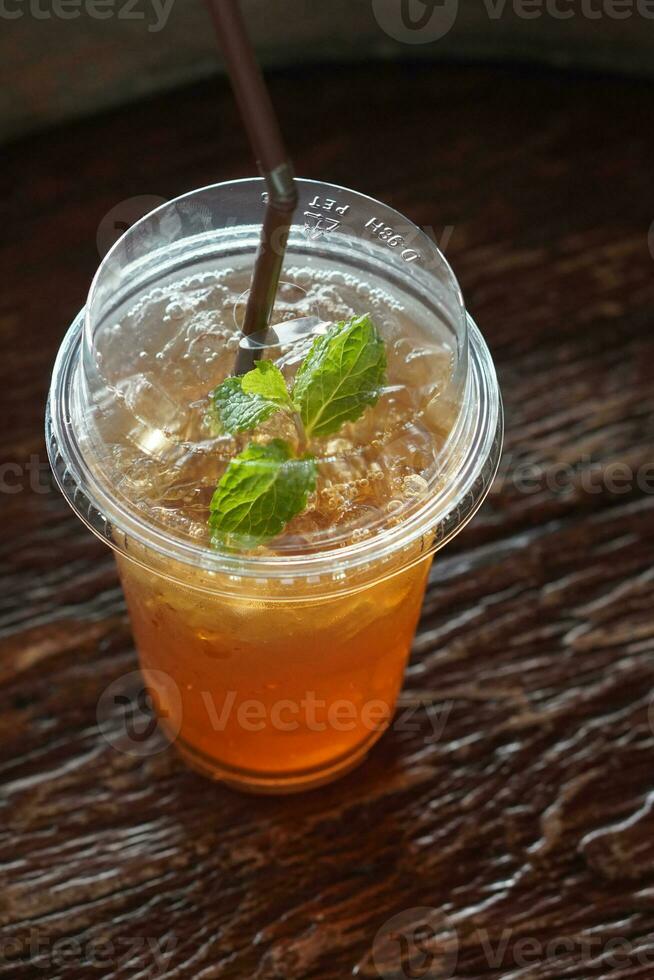 top view fresh lemon tea and ice in a plastic cup on wooden floor background, fruit, drink, health, banner, template, copy space photo