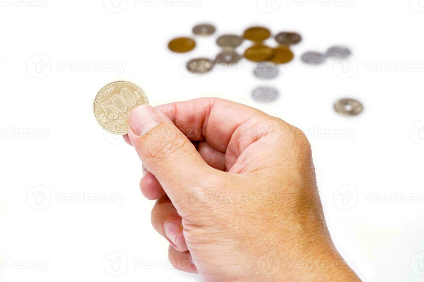 Image of hand picking up 500 Japan Yen currency coins from stack isolate on white background. Make with paths. photo