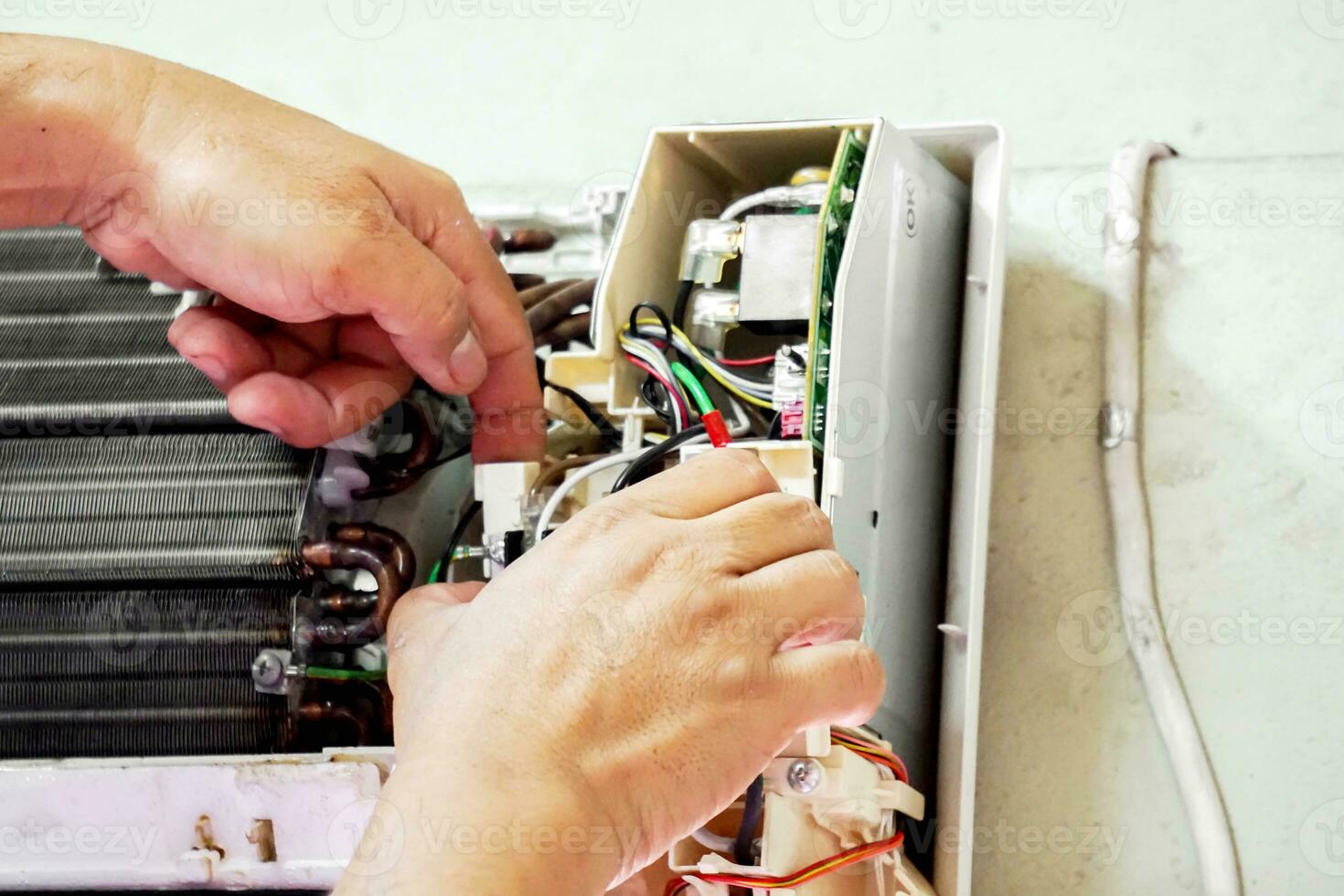 Closeup hands of electric repair technician fix an electronic board of home's air conditioner after washing in the bedroom. photo