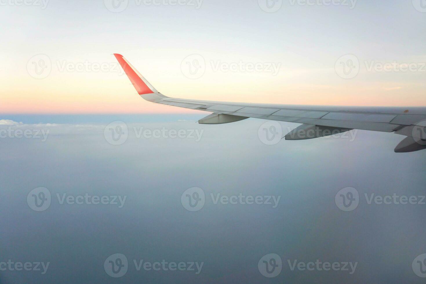 Outside window view of airplane with aircraft wing and sky of sunset background. photo