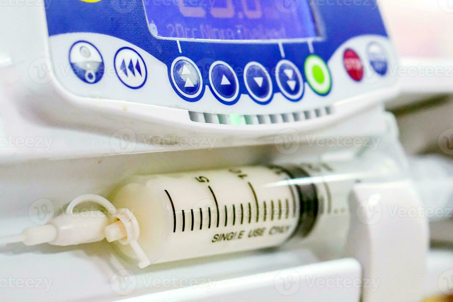 Closeup syringe pump machine pumping milk to sick newborn baby with monitor head and control buttons in hospital. photo