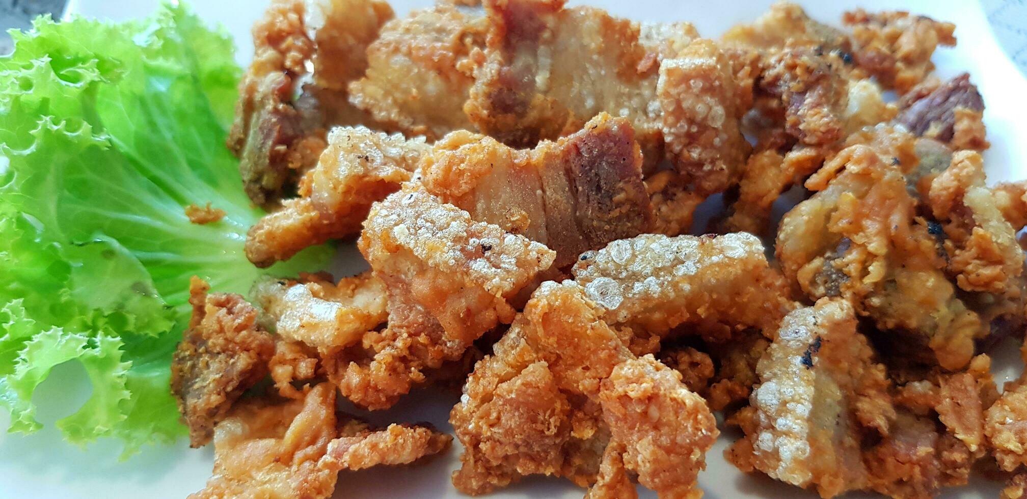 profundo frito crujiente Cerdo con verde repollo hoja en blanco plato a tailandés restaurante. asiático y grasa comida concepto foto