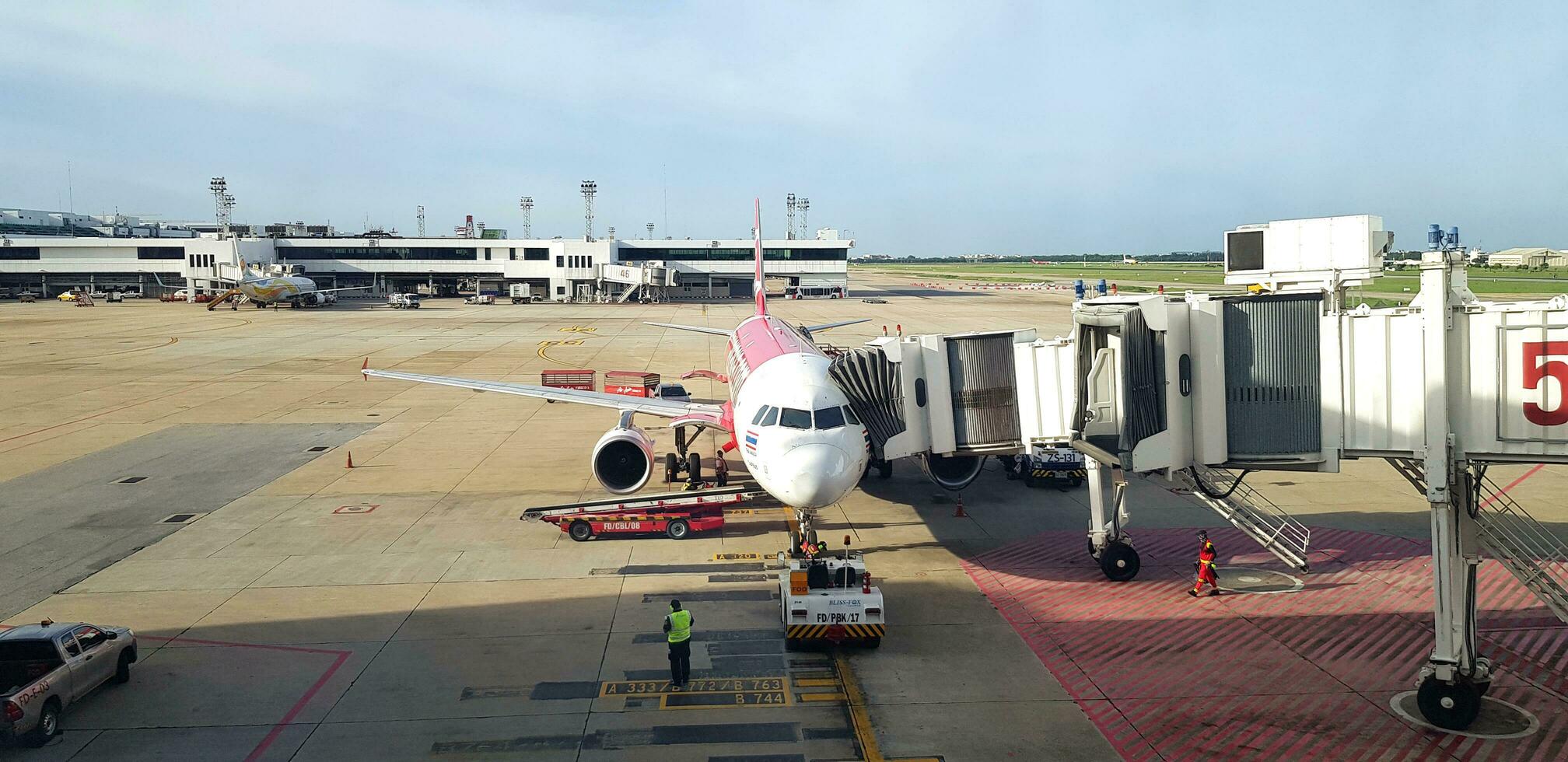 Songkhla, Thailand - May 28, 2023 Aircraft or airplane parked and waiting for passenger get inside with blue sky and terminal building background at Hat Yai airport. Transportation and vehicle photo