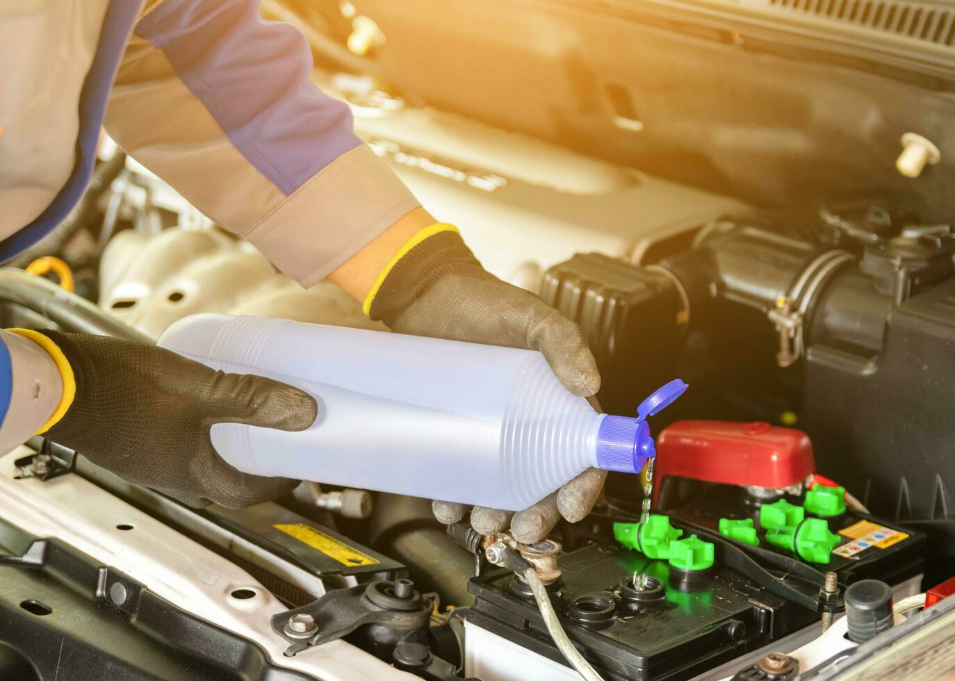 The mechanic adds distilled water and check the car battery photo