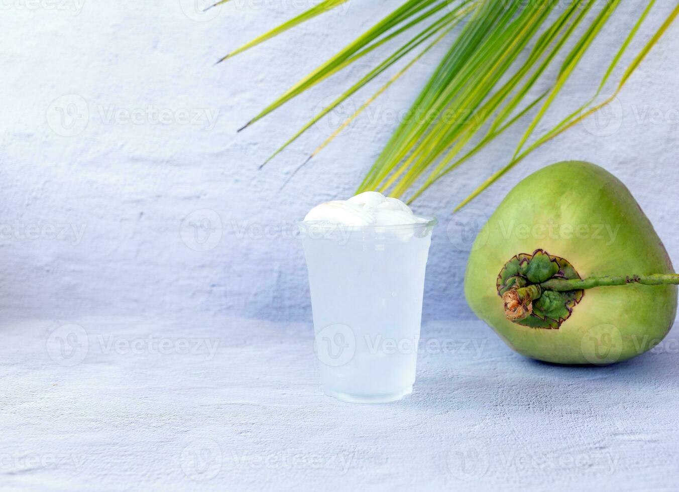 Ice coconut water drink in a plastic glass and coconut on white background photo