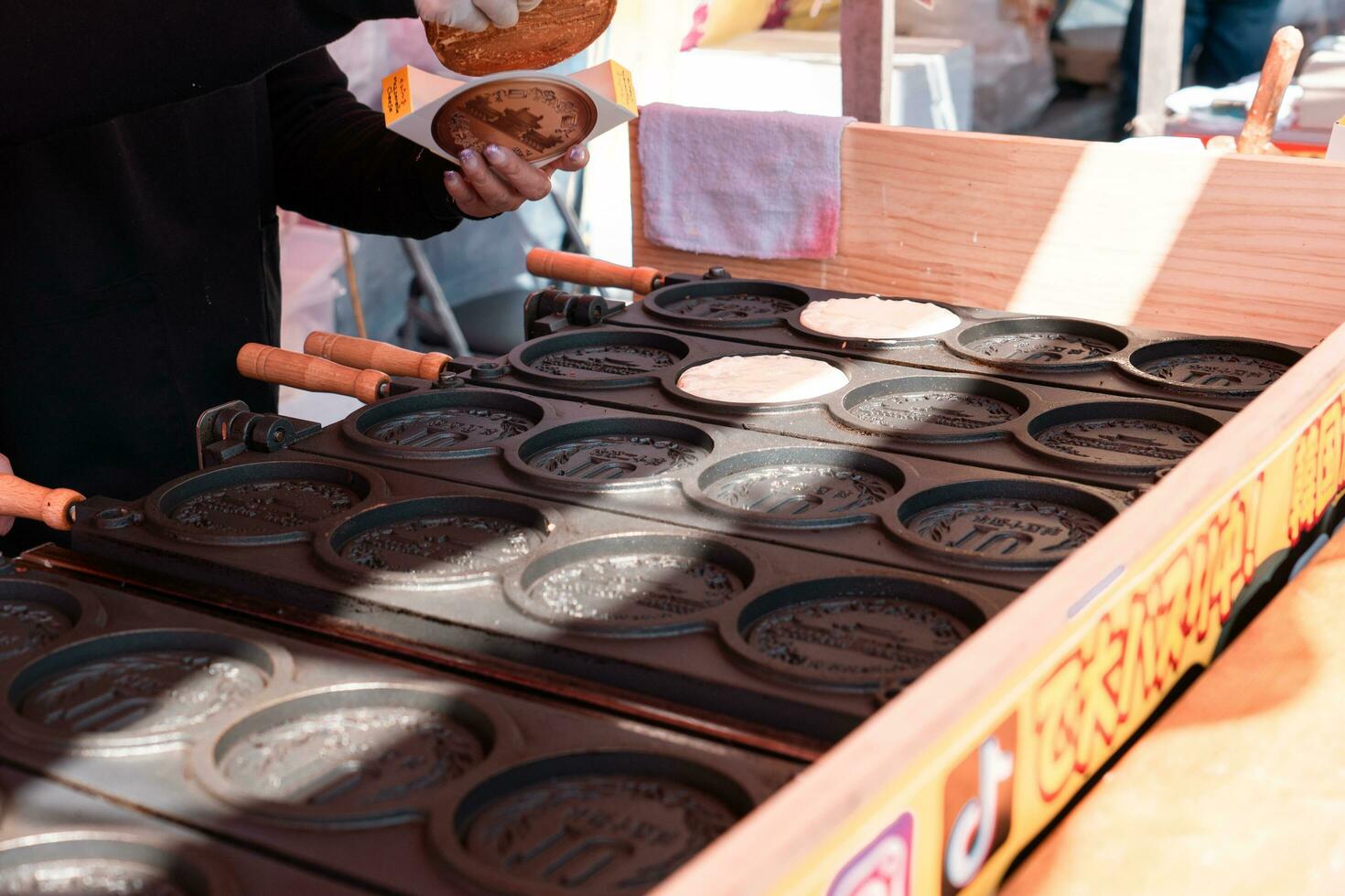 TOKYO, JAPAN - APRIL 9, 2023 Vender selling 10Yen coin shape pancake with mozzarella cheese in Sensoji temple photo