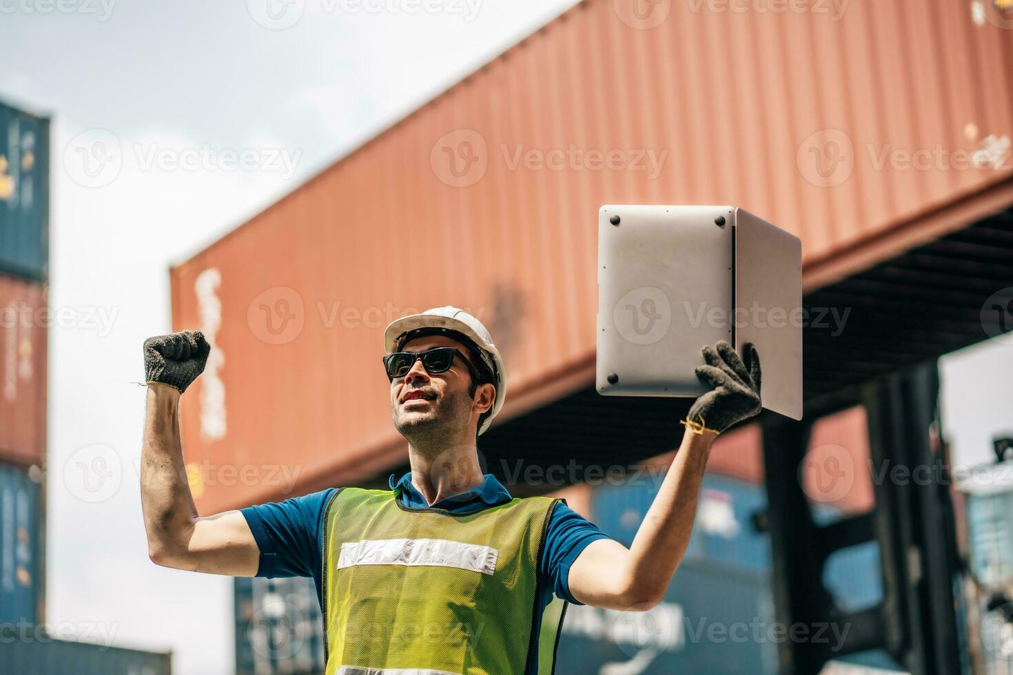 Engineer dock worker in protective safety jumpsuit uniform and with hardhat and use laptop computer at cargo container shipping warehouse. transportation import,export logistic industrial photo