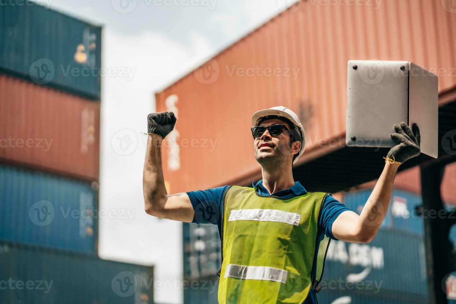 Engineer dock worker in protective safety jumpsuit uniform and with hardhat and use laptop computer at cargo container shipping warehouse. transportation import,export logistic industrial photo