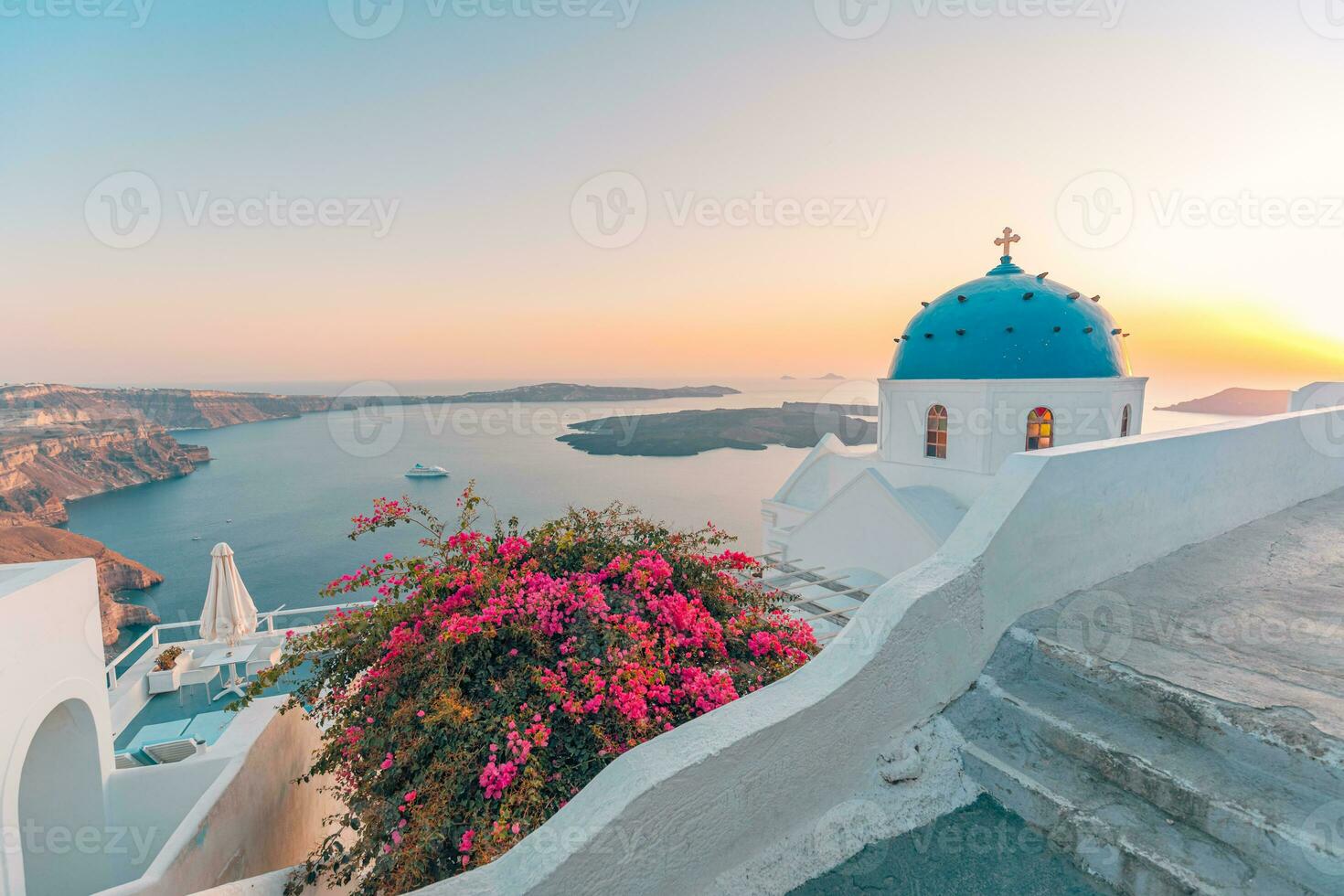 Santorini, Greece. Sunset landscape of traditional cycladic Santorini dome with flowers and stairs in foreground. Oia village, Santorini, Greece. Luxury summer vacations background. Peaceful travel photo