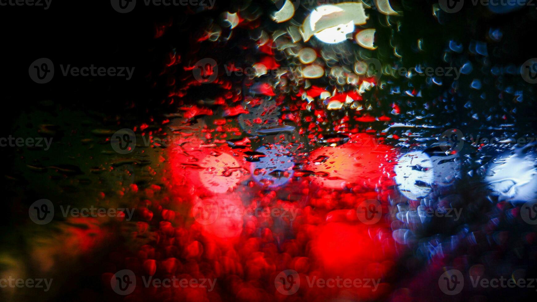 Raindrops on a car windscreen with colorful traffic background at night in Cibinong, West Java, Indonesia photo