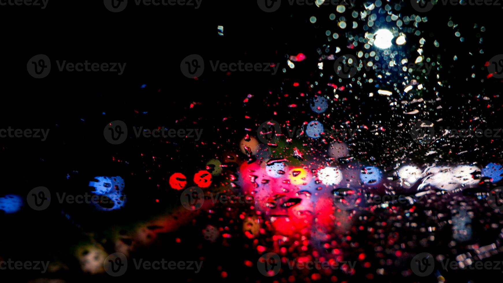 Raindrops on a car windscreen with colorful traffic background at night in Cibinong, West Java, Indonesia photo