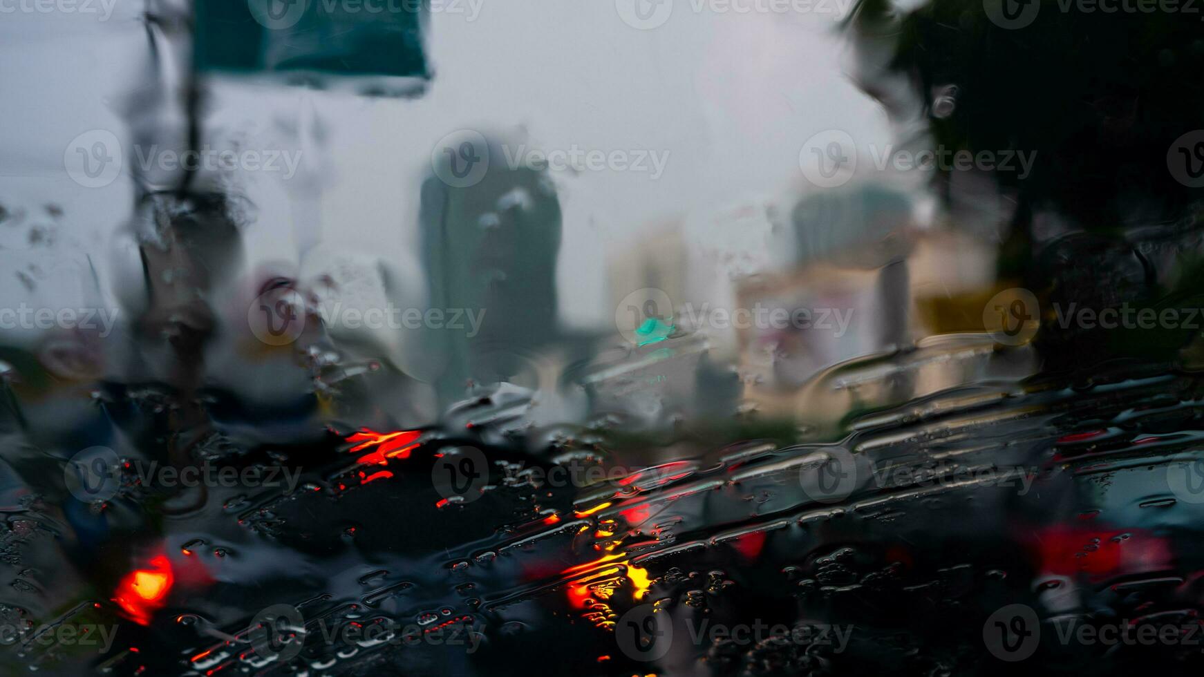 Raindrops on the windscreen of a car driving along the street on a sunny afternoon photo