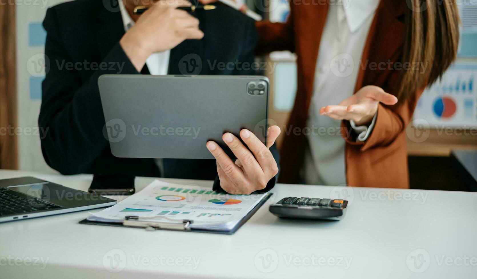 Business documents on office table with smart phone and calculator digital tablet and graph business with social network diagram and two colleagues discussing data working in the office photo