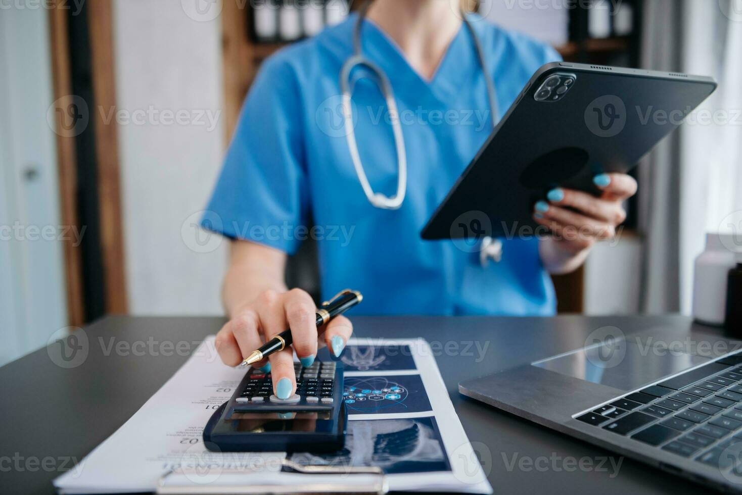Healthcare costs and fees concept.Hand of smart doctor used a calculator and smartphone, tablet for medical costs at hospital in morning light photo