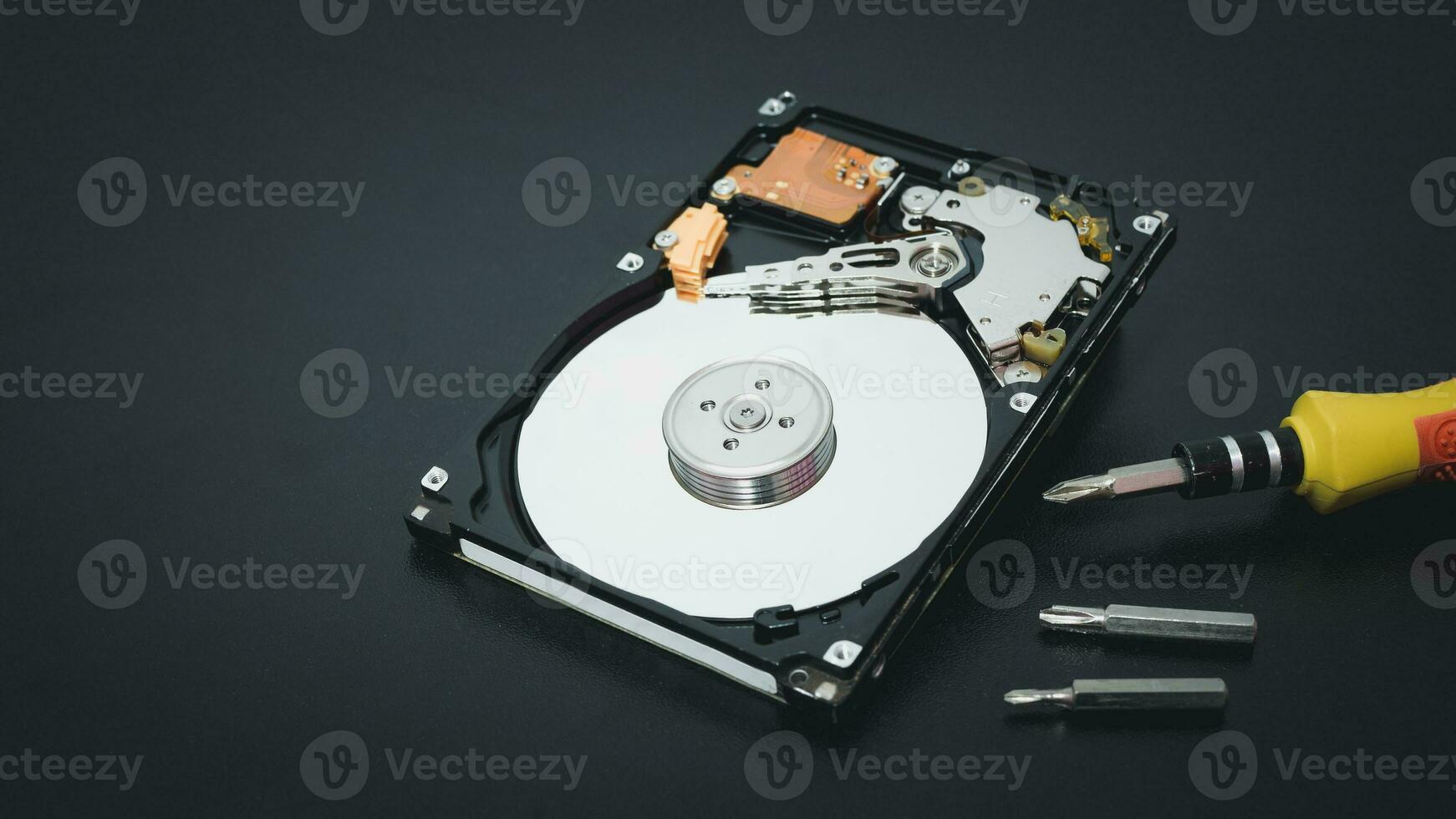 Memory repair concept. Repair of storage systems. Hard disk repair. Hard disk with screwdriver on dark background photo