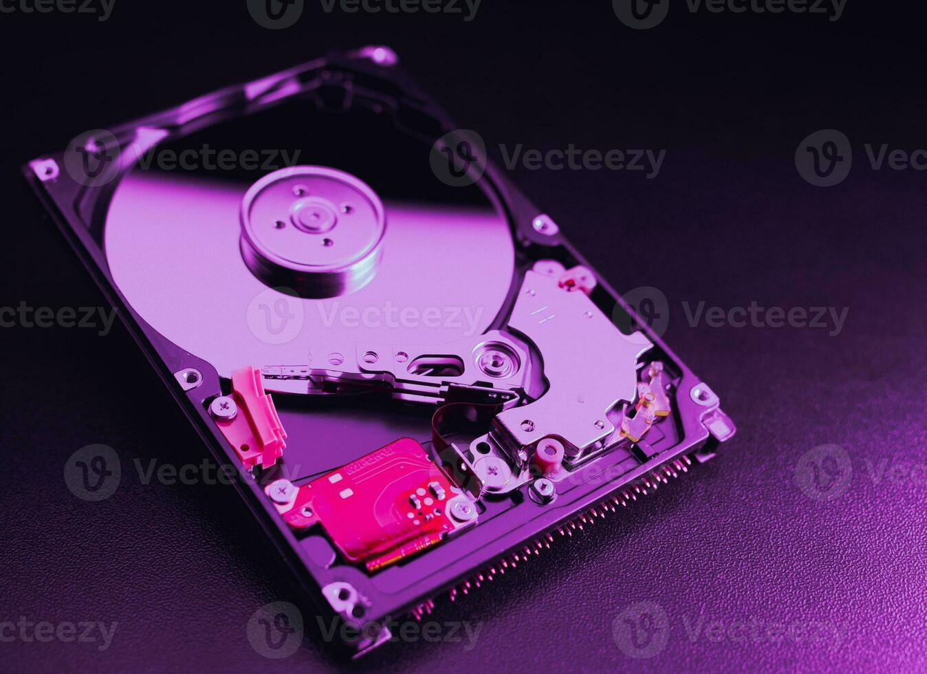 An open hard disk disassembled HDD of a computer or laptop lies on a purple surface. Computer hardware and accessories. Hard disk storage. photo