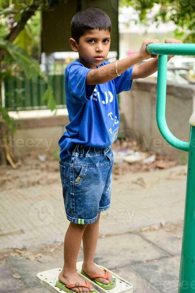 asiático chico haciendo rutina ejercicio en sociedad parque durante el Mañana tiempo. linda pequeño niño ejercicio y gimnasio a mantener él mismo ajuste para vida. niño ejercicio al aire libre disparar foto