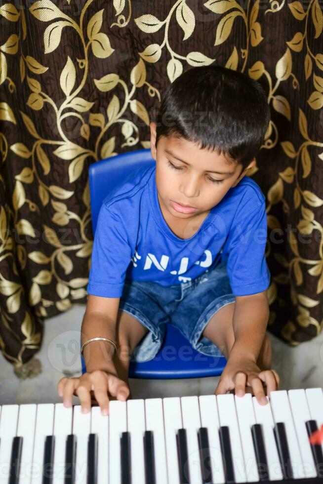 Asian boy playing the synthesizer or piano. Cute little kid learning how to play piano. Child's hands on the keyboard indoor. photo