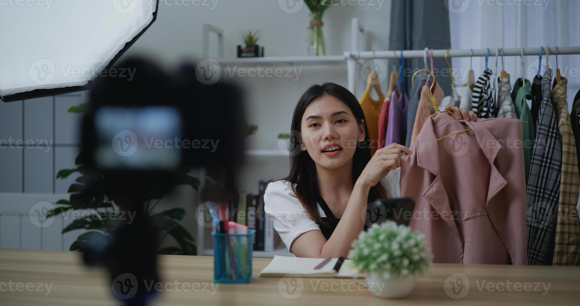 Young Beautiful Asian woman live streaming at clothes shop on digital camera photo