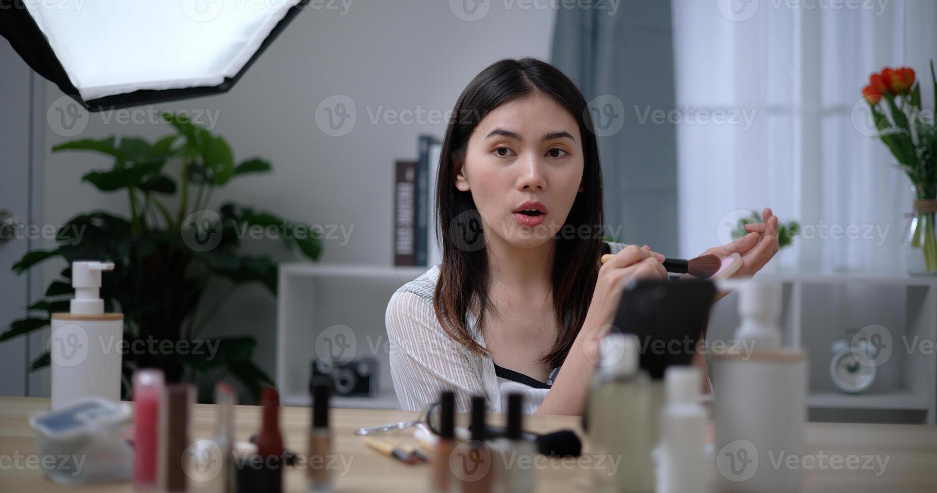 Beautiful young Asian woman blogger shows how to make up and use cosmetics photo