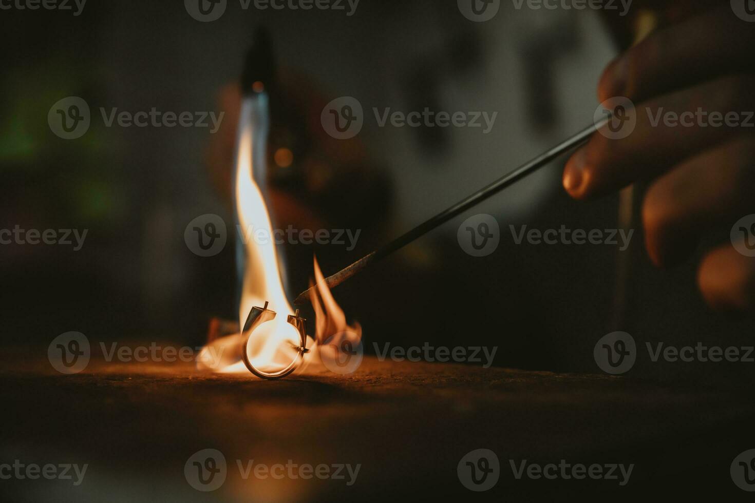 Detail of flame of jeweler's blowtorch while working on the gold ring on his workbench photo