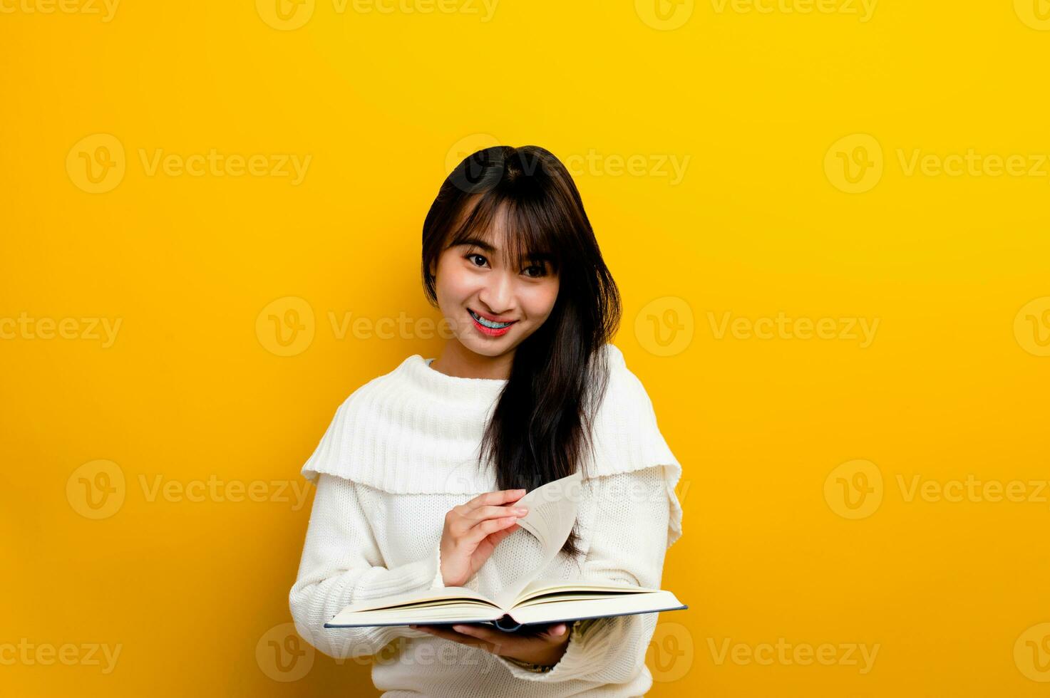 Read a book, study with the protagonist, seek knowledge, food for thought, girl reading a book and smiling. in the photo studio yellow backdrop