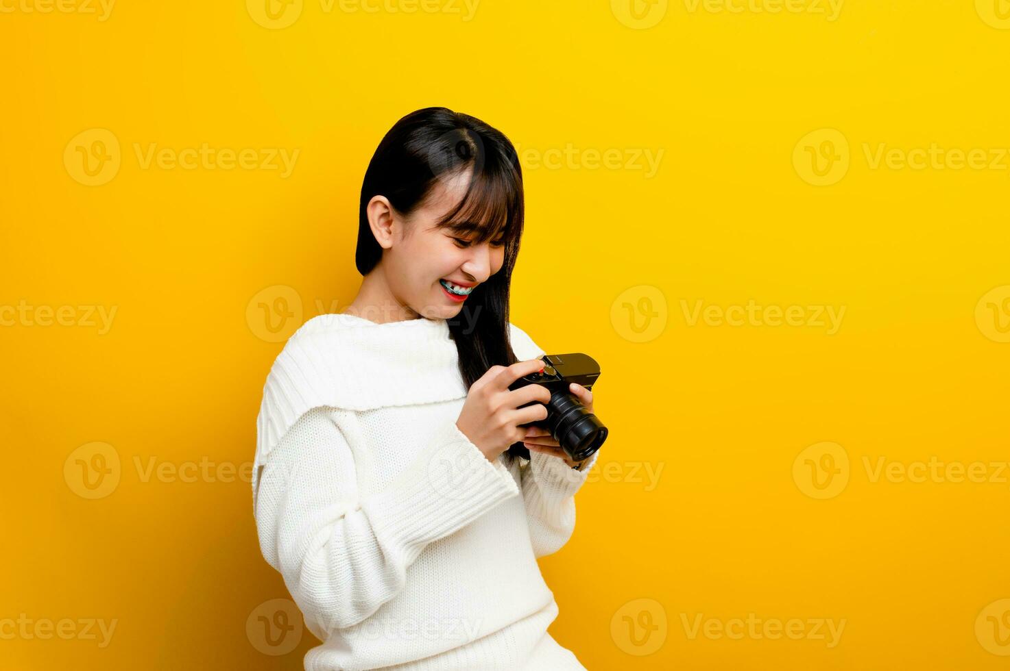 Female photographer with camera young women love taking pictures camera lover taking pictures in the yellow studio photo