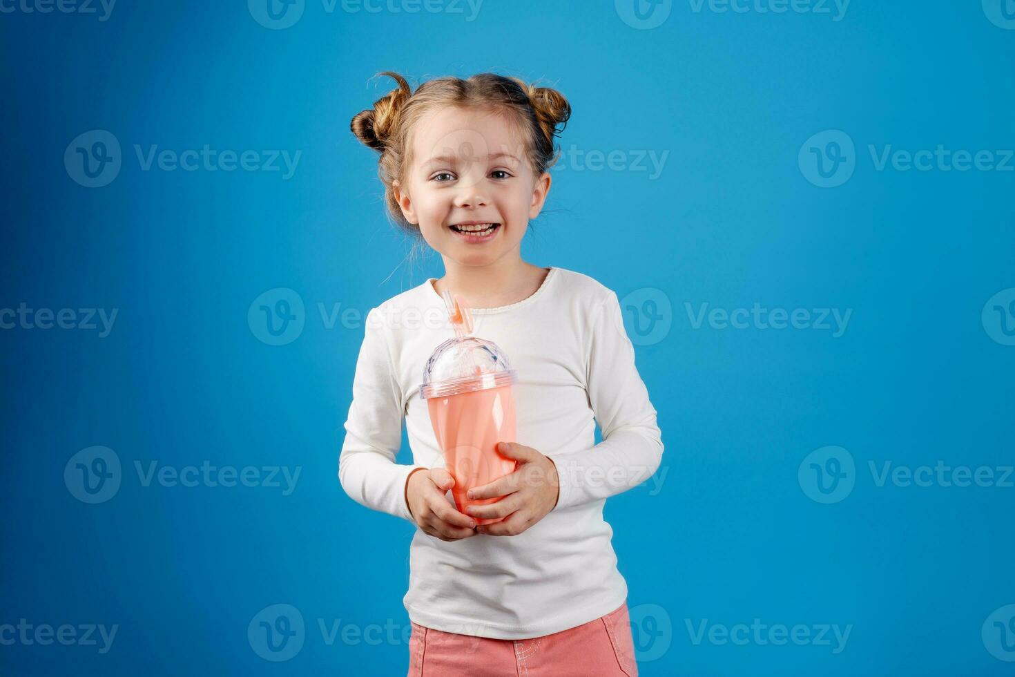 portrait of a small happy girl of Slavic appearance drinking a cocktail of berries. place for text photo