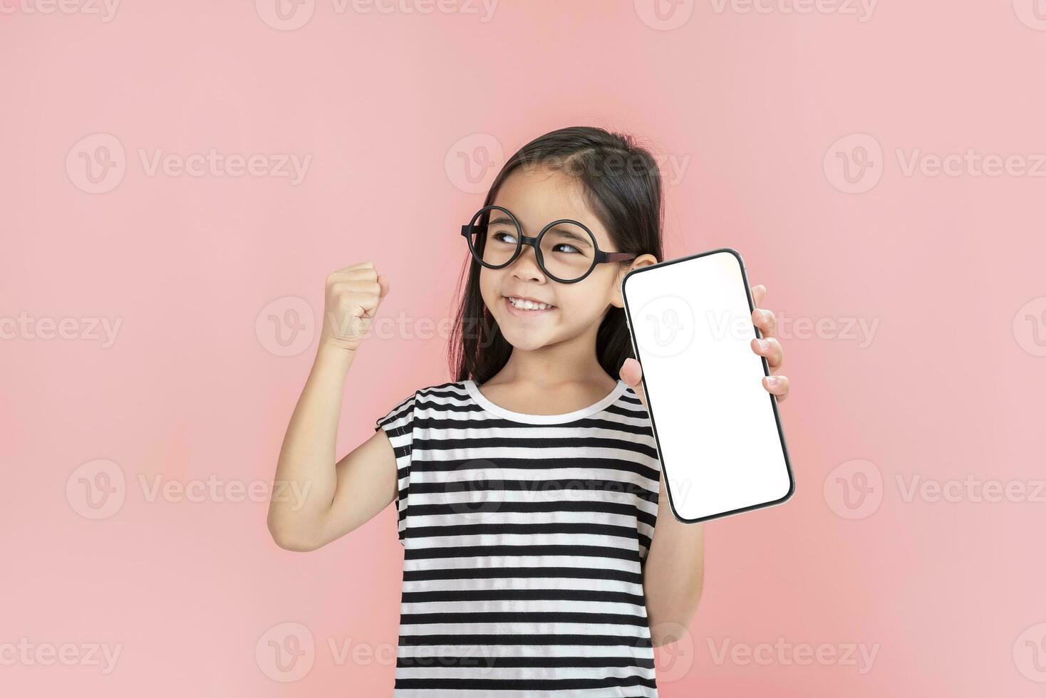 Asian little girl holding smartphone mockup of blank screen and smiling on white background. photo