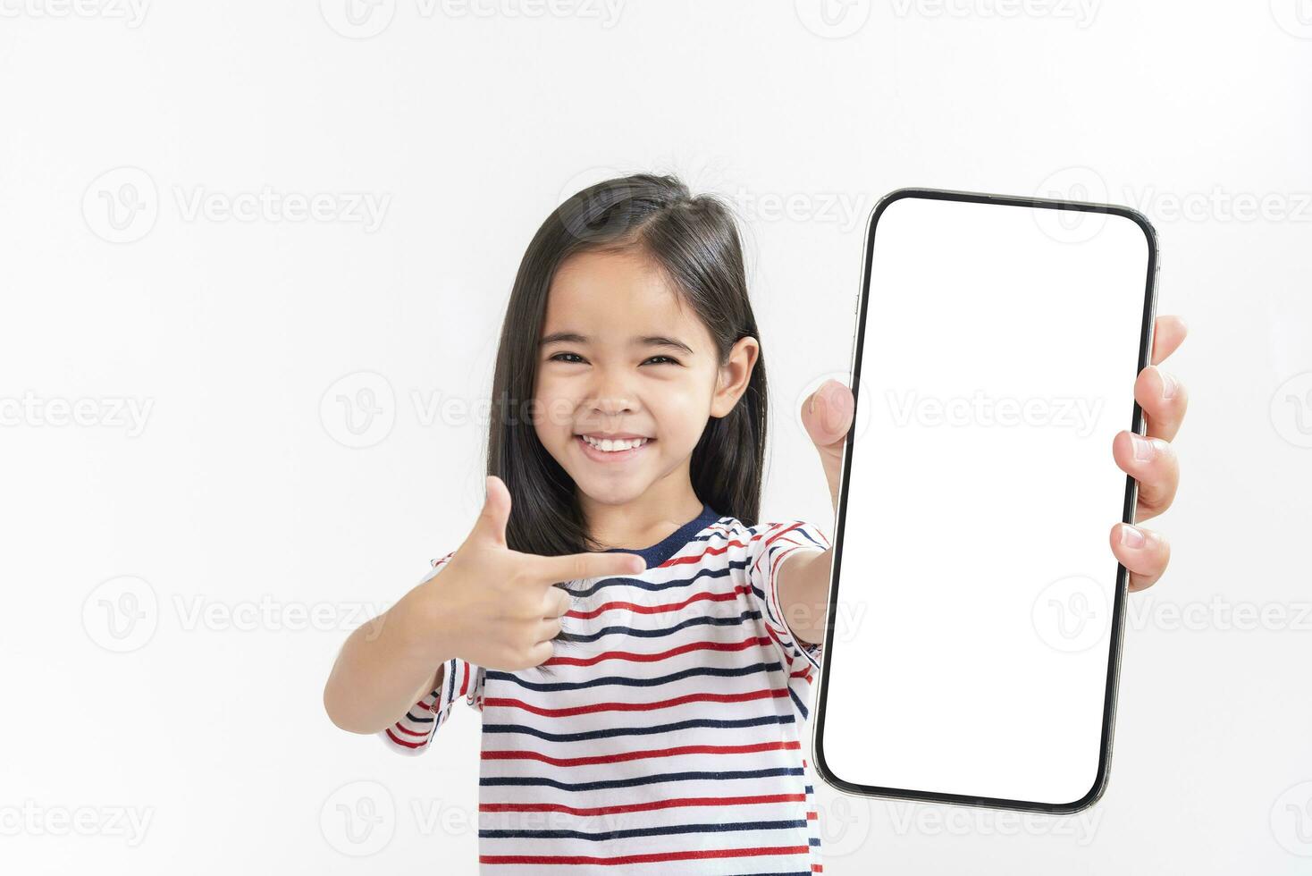 Asian little girl holding smartphone mockup of blank screen and smiling on white background. photo