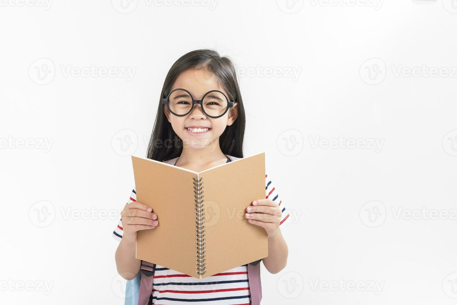 schoolgirl hugging book wearing backpack smiling isolated on white background photo