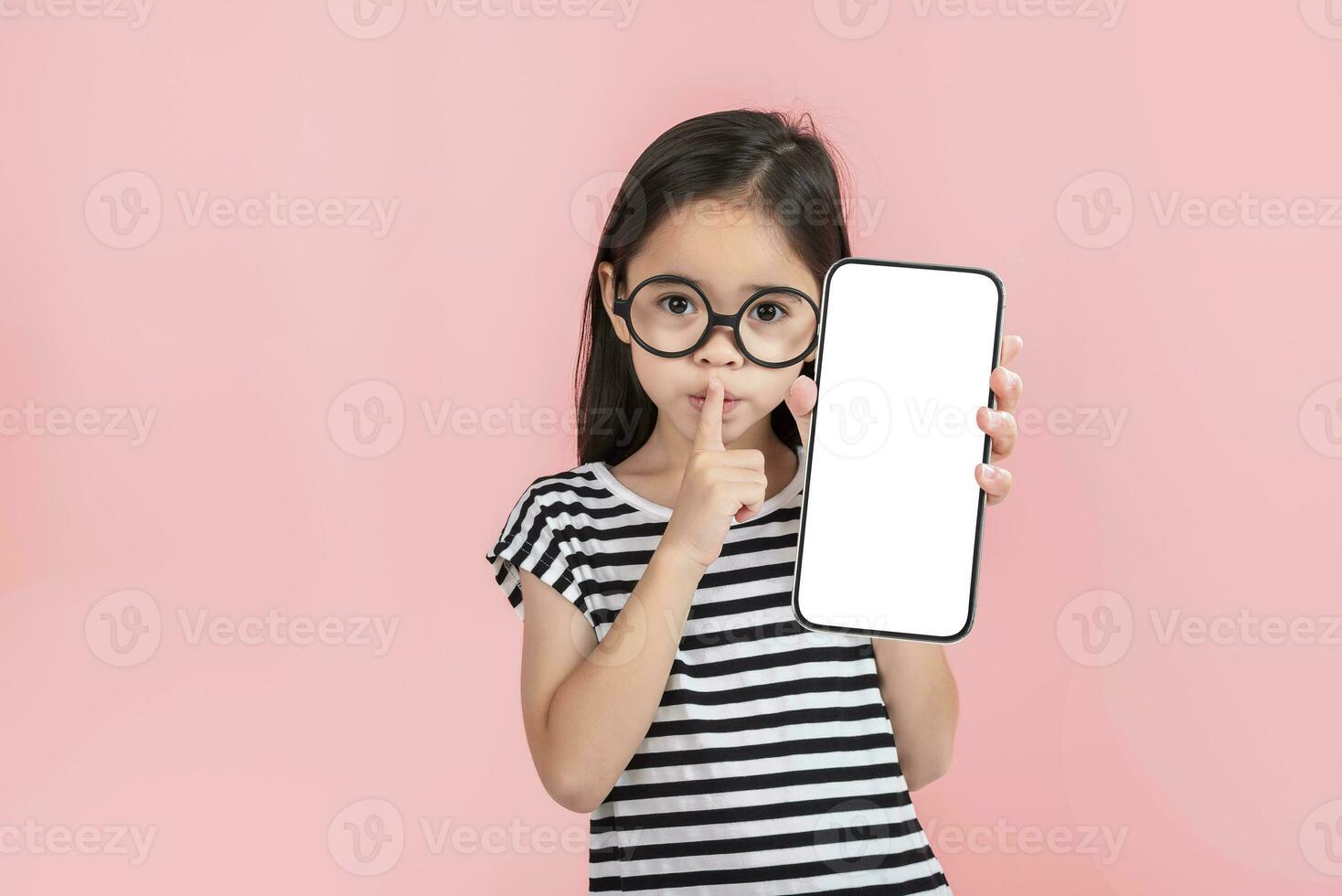 Asian little girl holding smartphone mockup of blank screen and smiling on white background. photo