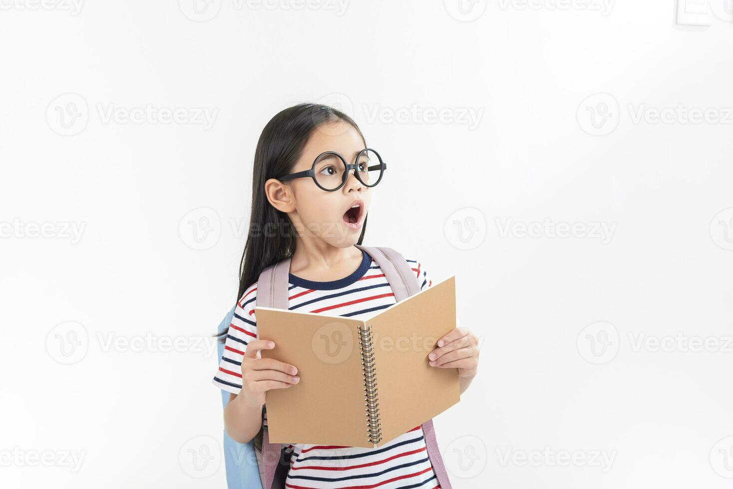 schoolgirl hugging book wearing backpack smiling isolated on white background photo