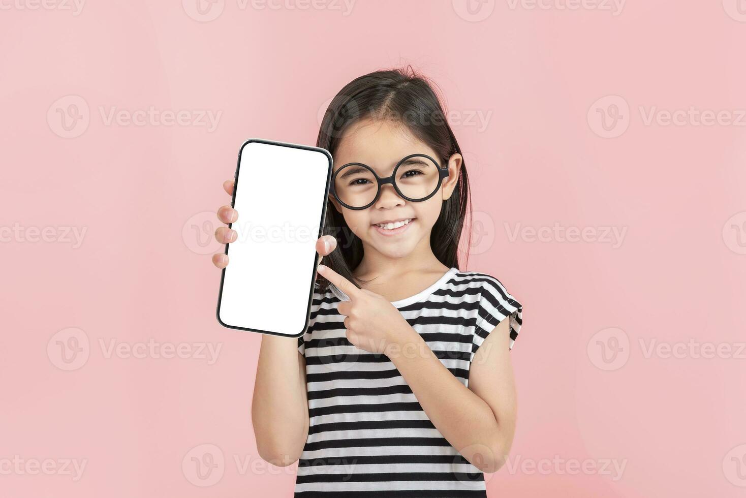 Asian little girl holding smartphone mockup of blank screen and smiling on white background. photo