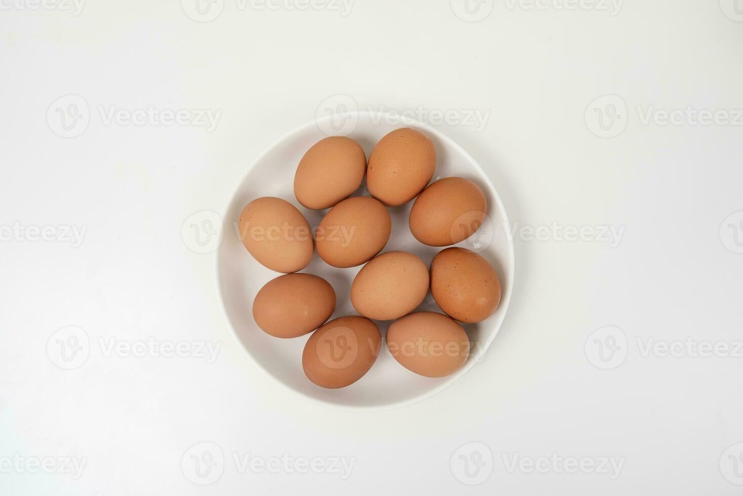 Top view of raw brown eggs on wooden plate isolated on white background. photo