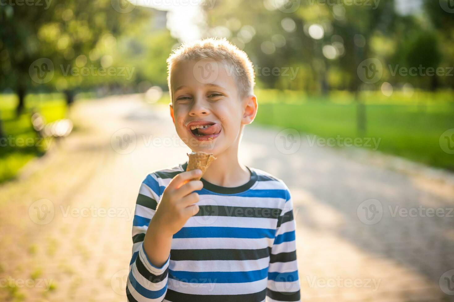 pequeño chico comiendo hielo crema en el parque foto