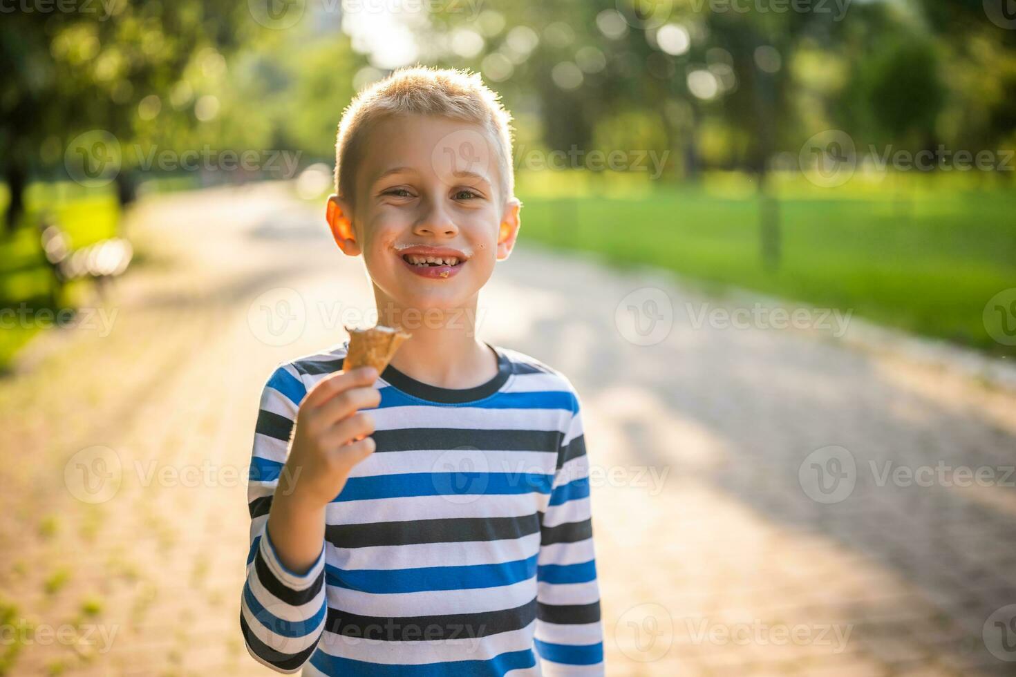 pequeño chico comiendo hielo crema en el parque foto