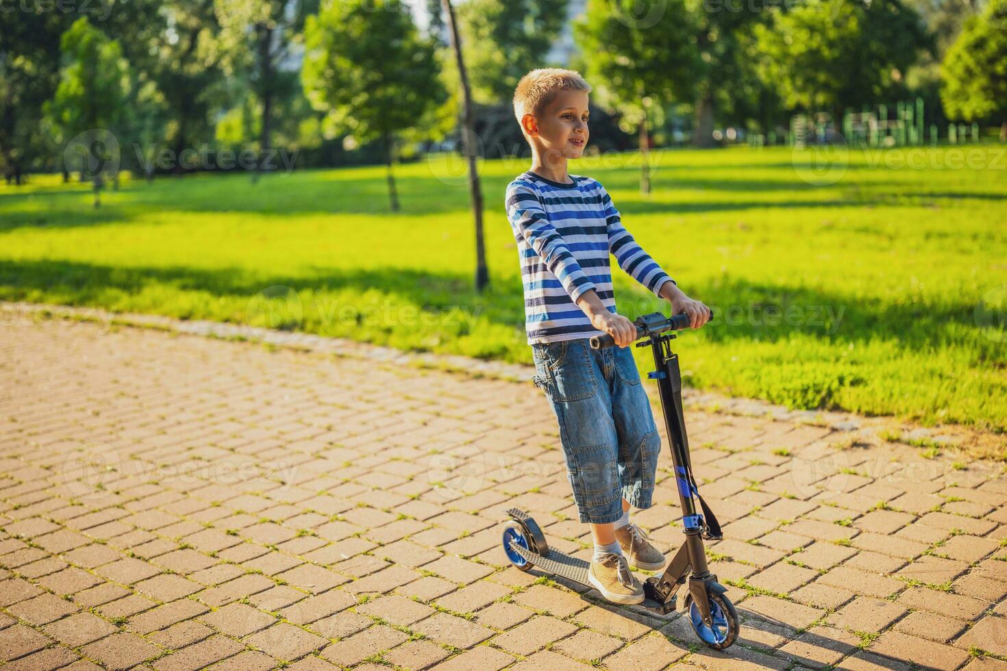 Little boy riding a scooter in the park photo