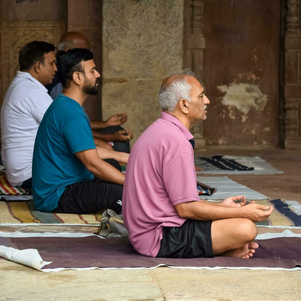 New Delhi, India, May 31 2023 - Group Yoga exercise class for people of different age in Lodhi Garden, International Yoga Day, Big group of adults attending a yoga class in park photo