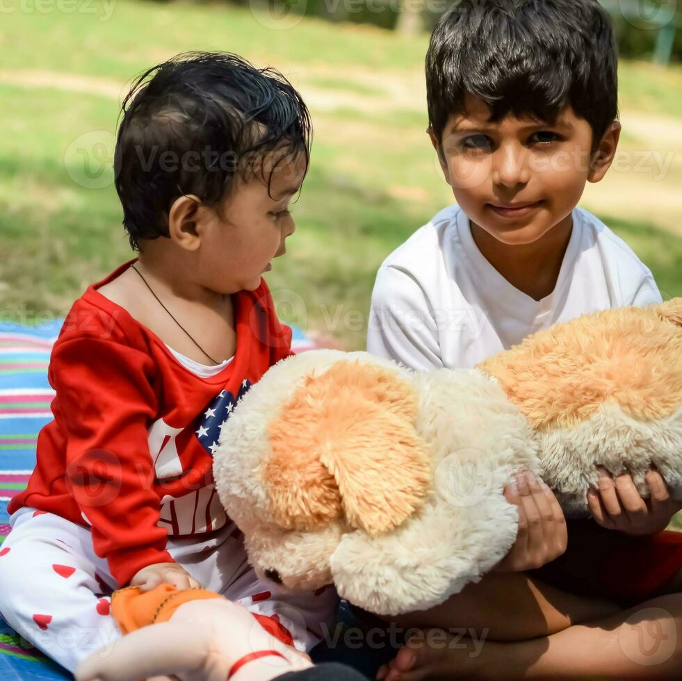 dos contento Niños en sociedad parque, contento asiático hermanos quien son sonriente felizmente juntos. hermanos jugar al aire libre en verano, mejor amigos. niñito bebé chico jugando con su contento hermano en el jardín foto