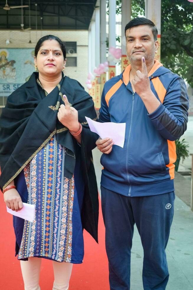 New Delhi, India - December 04 2022 - Unidentified people showing their ink-marked fingers after casting votes in front of polling booth of east Delhi area for MCD local body Elections 2022 photo