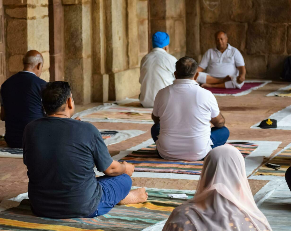 New Delhi, India, May 31 2023 - Group Yoga exercise class for people of different age in Lodhi Garden, International Yoga Day, Big group of adults attending a yoga class in park photo