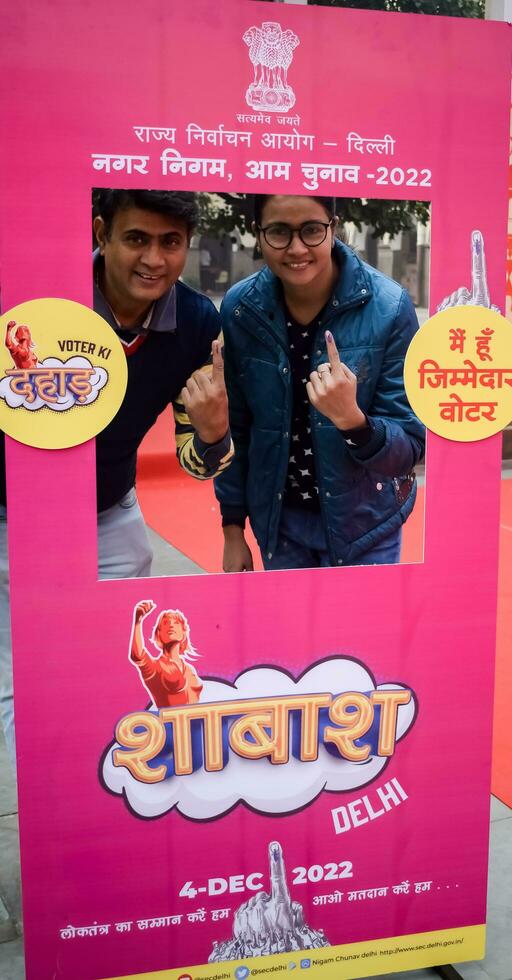 New Delhi, India - December 04 2022 - Unidentified people showing their ink-marked fingers after casting votes in front of polling booth of east Delhi area for MCD local body Elections 2022 photo