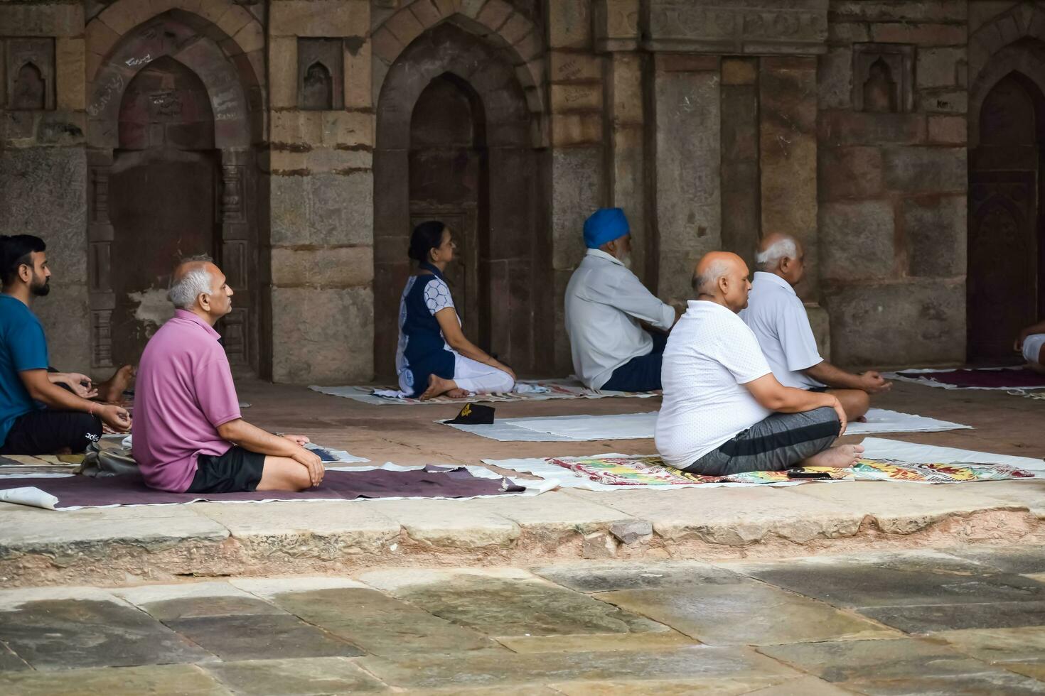 New Delhi, India, May 31 2023 - Group Yoga exercise class for people of different age in Lodhi Garden, International Yoga Day, Big group of adults attending a yoga class in park photo