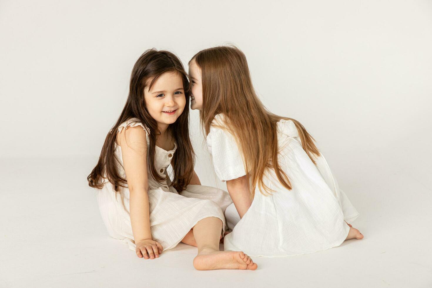 Cute kids, portrait of happy little girls in white summer dresses on white background. Children fashion, style concept. A happy childhood, children's world, the concept of stylish children's clothing photo