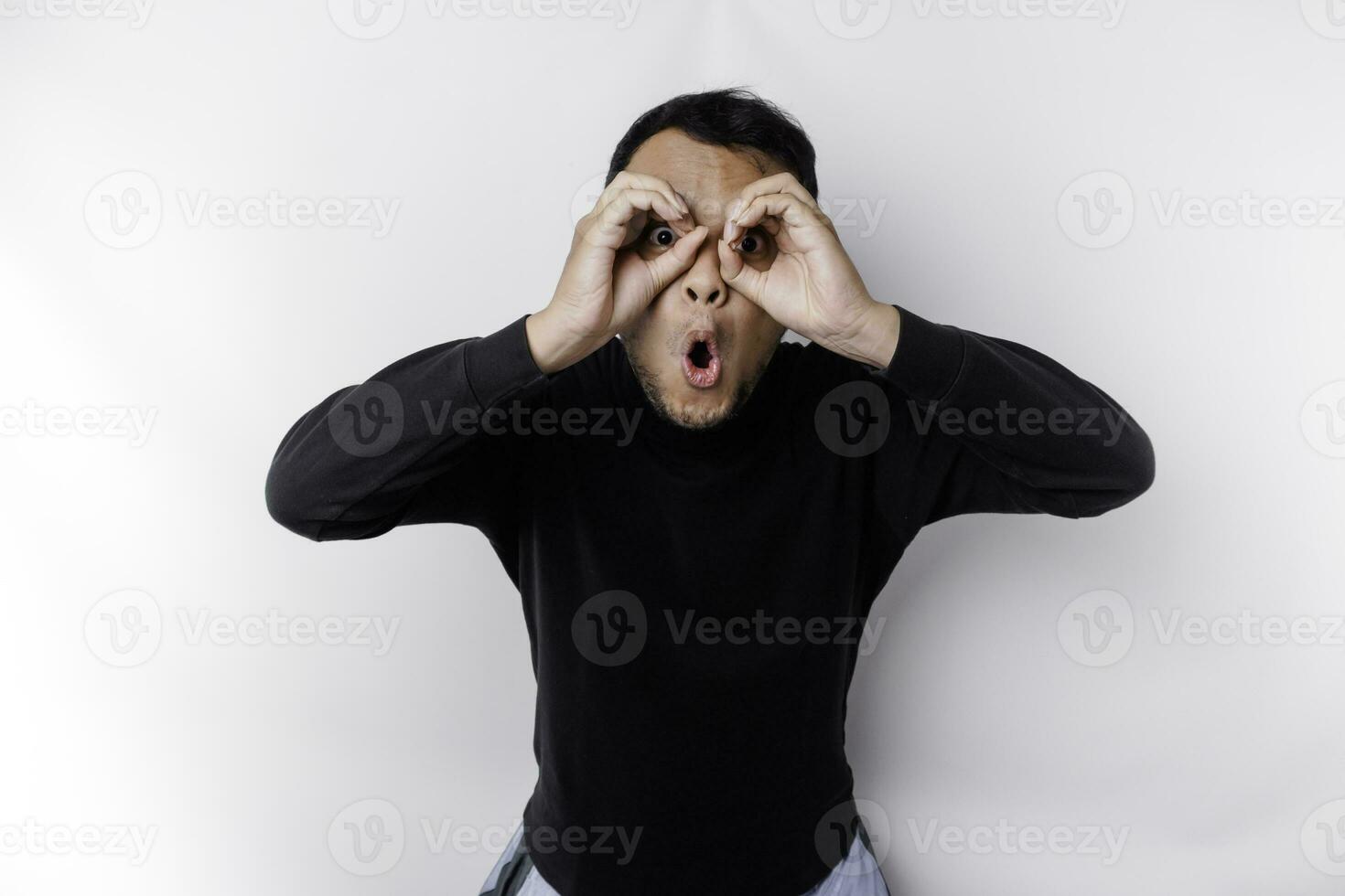 Funny obvious peeking Asian man in black shirt isolated on white background. photo