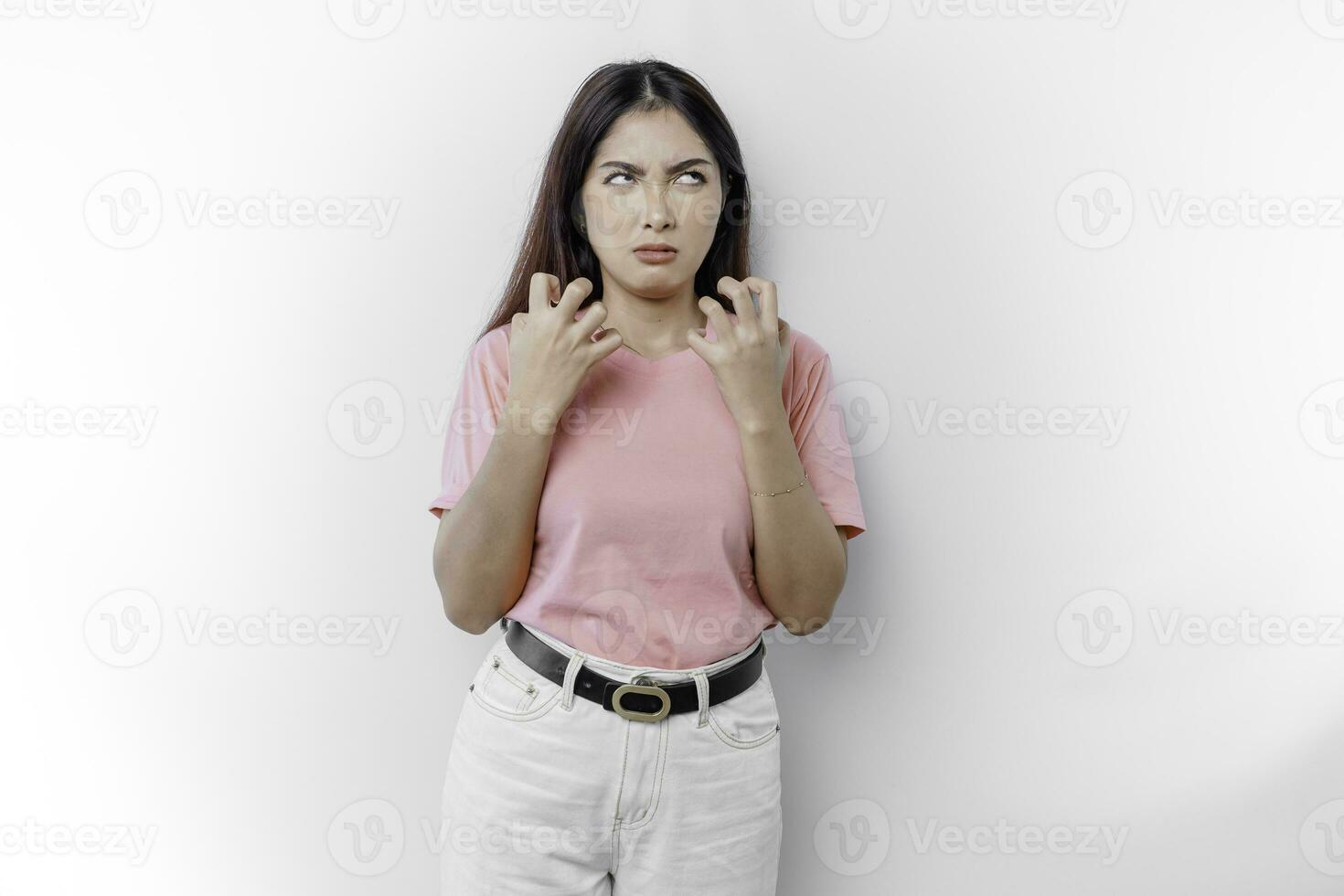 A dissatisfied young Asian woman looks at the camera posing on a white background, disgruntled girl with irritated face expressions show negative attitude concept image photo